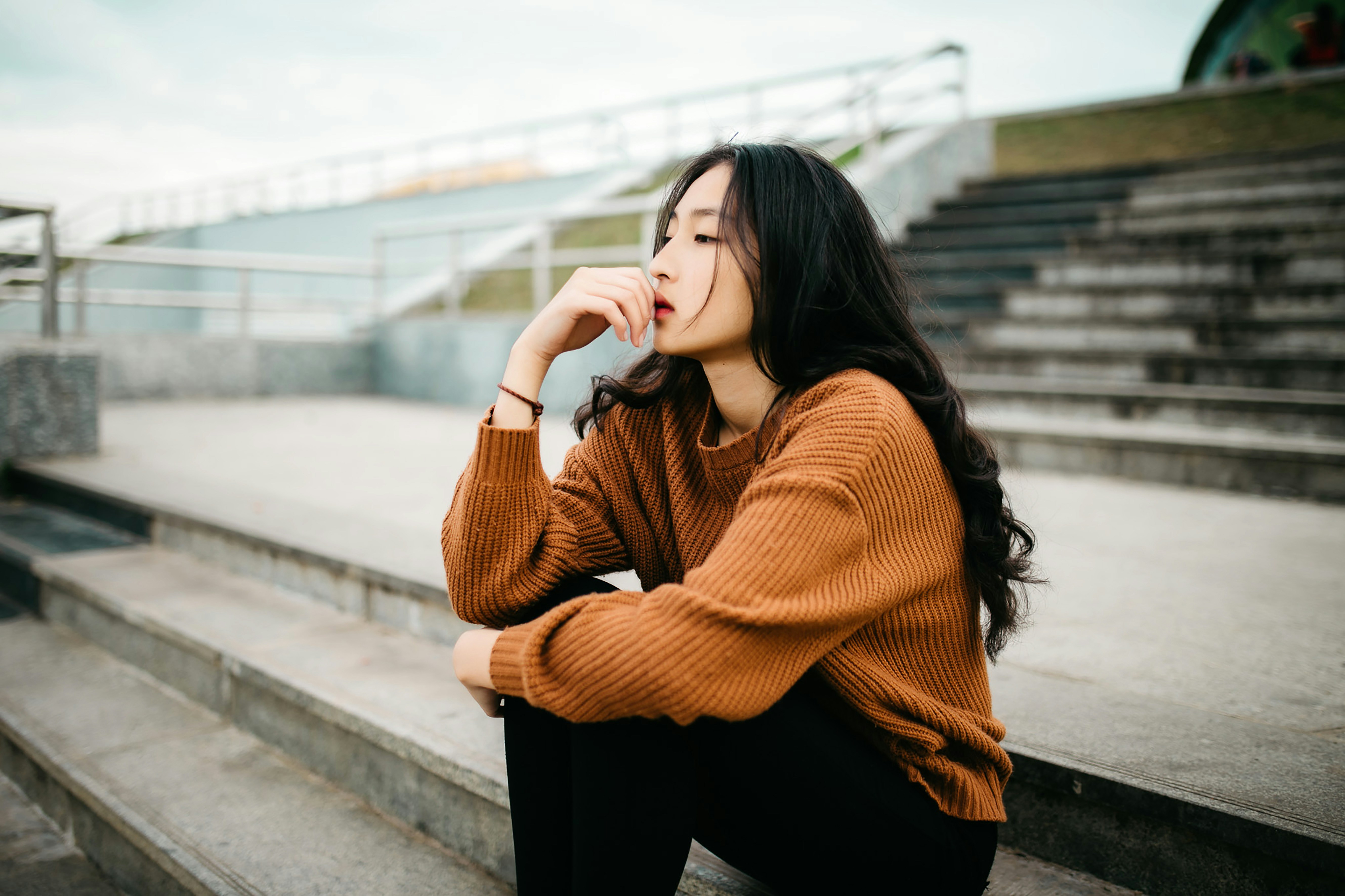 Asian woman pondering while sitting on a stairway